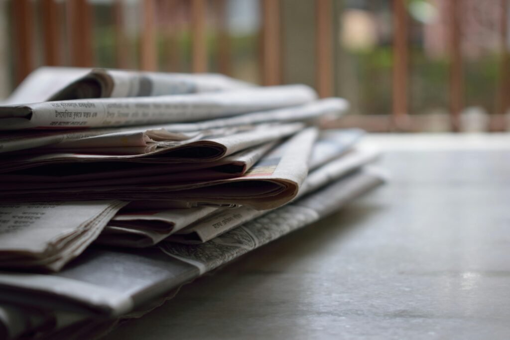 Home A close-up of a stack of newspapers resting on a desk, symbolizing information and media.